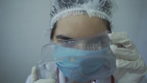 close up view of lady medical doctor wearing protective safety goggles infront of mirror. camera poi