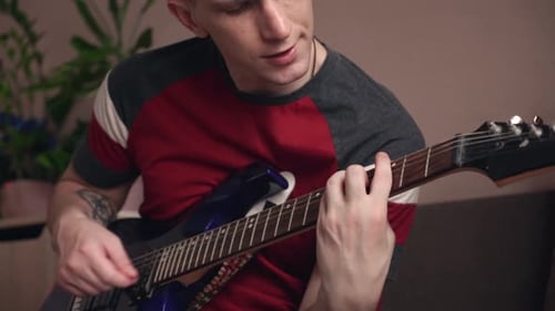 Young Adult Plays Electric Guitar Indoors