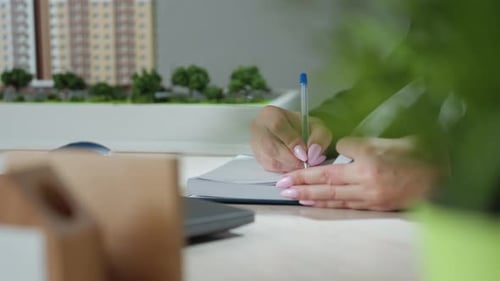 Close Up of Lady Writing with Polished Pink Nails in Office Workspace