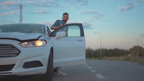Male Driver with Smartphone Getting Out of Modern Car Looking on Breakdown Hood of Vehicle Young