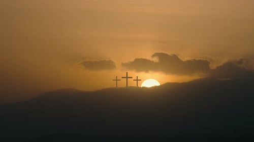 Three Silhouetted Crosses on a Hill at Sunrise
