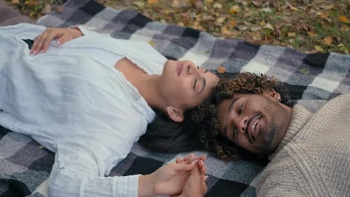 Couple Lying Head-to-Head Holding Hands in Park