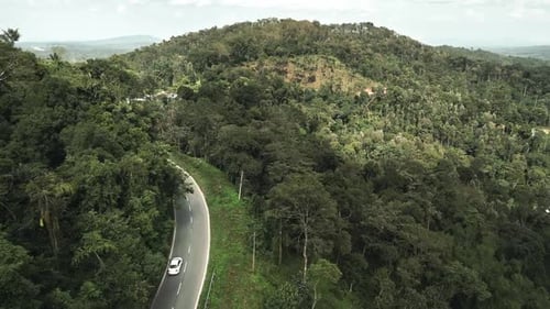 Aerial drone footage captures car moving along winding highway, set against breathtaking backdrop of