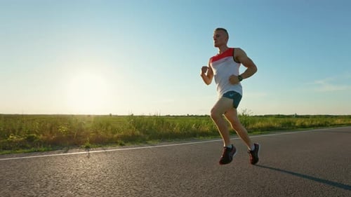 Strong Sportsman with Muscles Running Quickly in Road on Asphalt