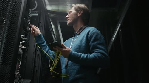 Engineer Using Tablet in Data Center while Checking Server Rack