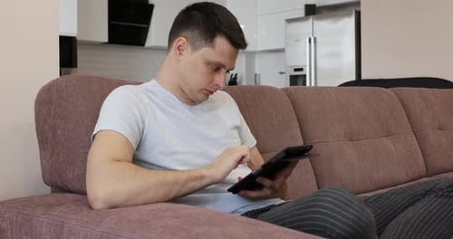 Man Using Tablet Device on Couch Indoors
