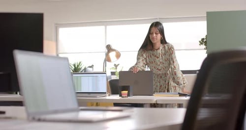 Biracial casual businesswoman closing laptop in office, slow motion