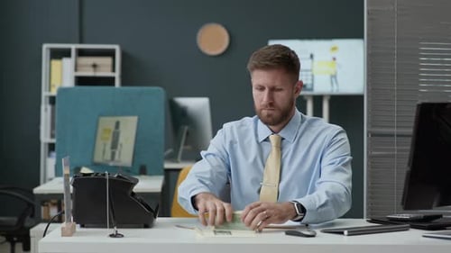 Bank Clerk Filling Counting Machine with Banknotes and Talking to Colleague