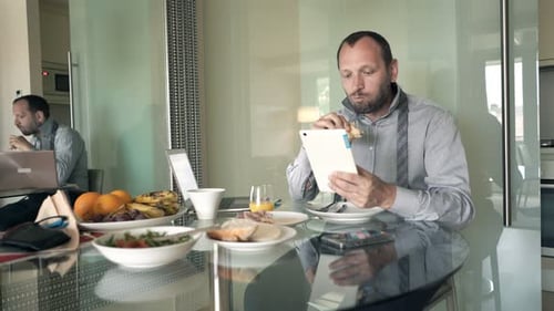 Man using Tablet While Eating Breakfast at Home