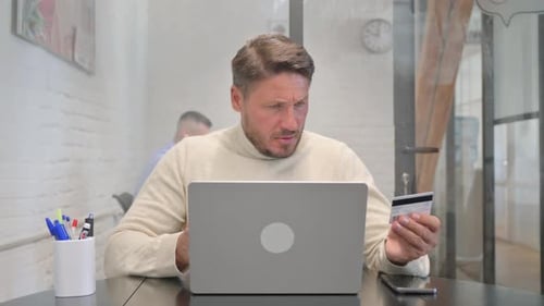 Man Using Laptop and Credit Card at Desk