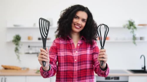 Woman Holding Spatula and Whisk in Kitchen