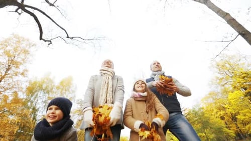 Happy family enjoying a sunny autumn day playing with leaves in a park