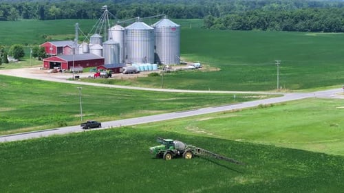 Tracteur pulvérisateur agricole épandant un engrais pesticide chimique sur des cultures en croissance sur un champ agricole