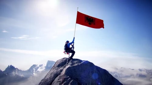 Alpiniste tenant le drapeau albanais au sommet de la montagne
