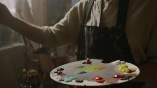 Artist Mixing Paints on Palette in Bright Studio