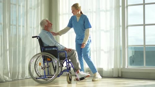 Caring Nurse Comforts Senior Patient in Wheelchair