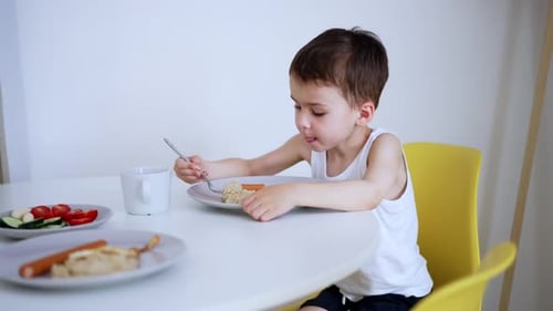 Boy with Brown Hair Eats Food at Table
