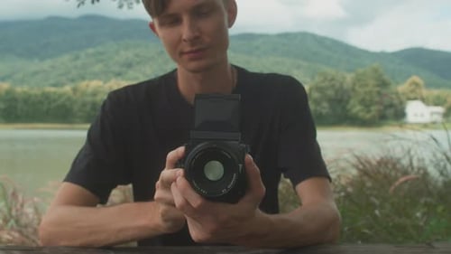 Young Adult Holding Camera by a Lake