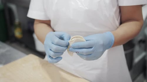 Worker Preparing Dumplings in Kitchen with Gloves
