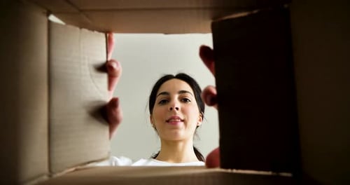 Woman Smiling and Reaching into a Cardboard Box
