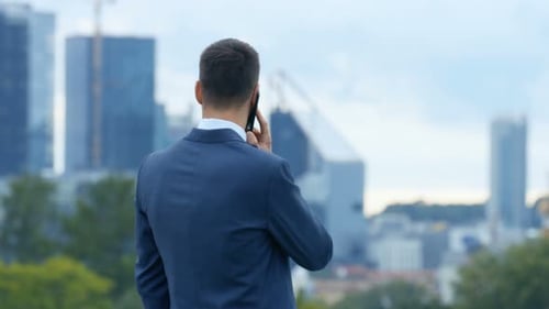 Medium Shot of the Confident Business Man Talking on the Phone. He Stands with His Back to The Big