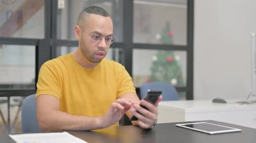 Man Celebrates Success Using Phone in Office
