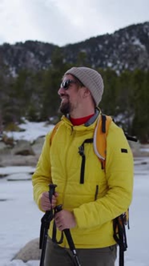 Hiker Walking in Snowy Mountain Forest Trail with Backpack and Trekking Poles