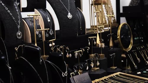 Jewellery at a market stall in slow motion. Stall lined with gold and silver necklaces and earrings.