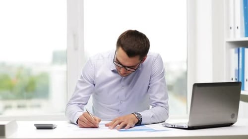 Busy hispanic businessman reviews financial reports with laptop in office