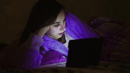 Woman Enjoying Tablet Pc Entertainment At Night In The Bed