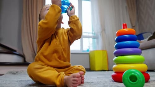 Cute baby boy drinks from bottle spilling the water.