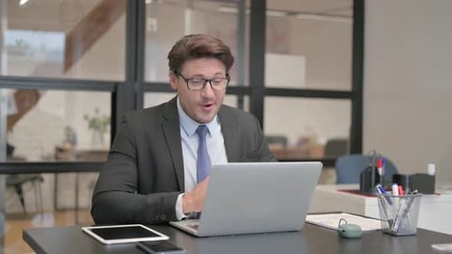 Middle Aged Businessman Chatting Online on Laptop while Sitting in Office