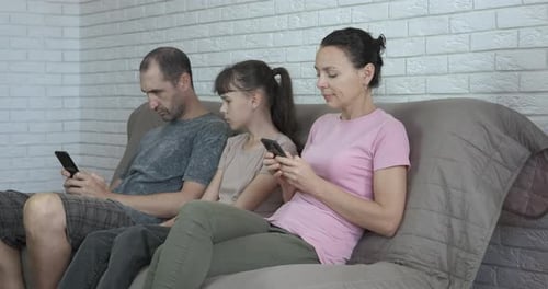 Family on Couch All Using Phones