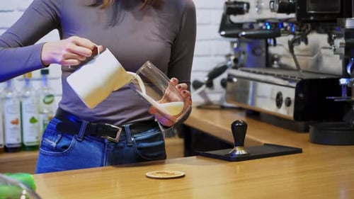 Female barista making cup of coffee while standing behind cafe counter