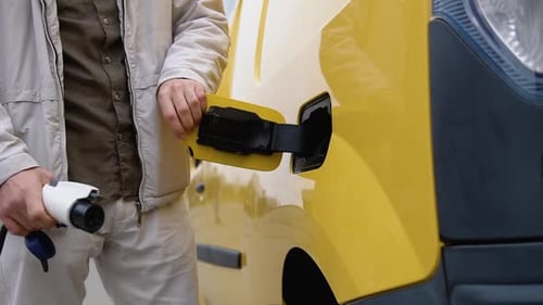 Männliche Hand steckt den Stromanschluss in das Cargo-EV-Auto
