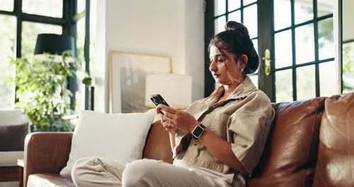 Young Woman Using Phone on Brown Leather Couch