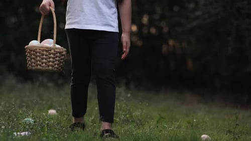 Zeitlupe eines kleinen Mädchens, das während einer Ostereiersuche auf grünem Gras läuft und einen Korb trägt