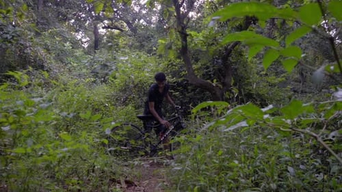 Man Drinking Water Next to His Bike in Forest