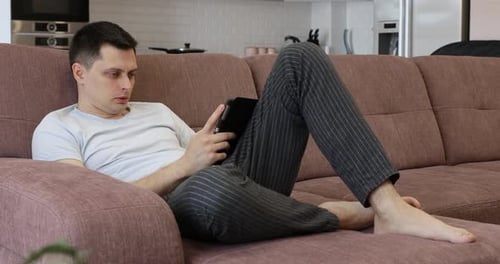 Man Relaxing With Tablet on Couch Indoors