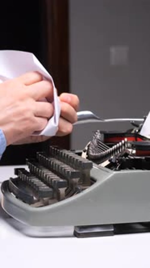 Man Crumples Paper at Typewriter in Frustration