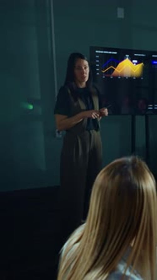 Business Presentation by Woman to Attendees in Dark Office