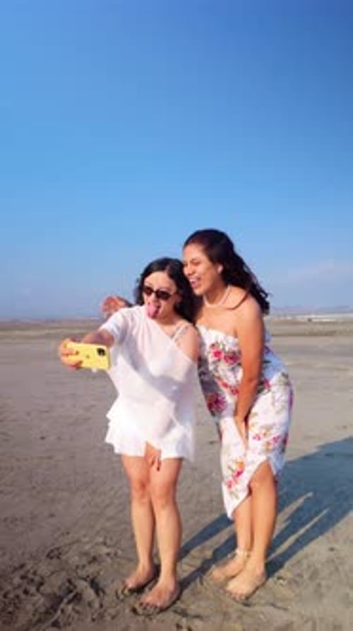 Two cheerful young women taking a selfie at the beach