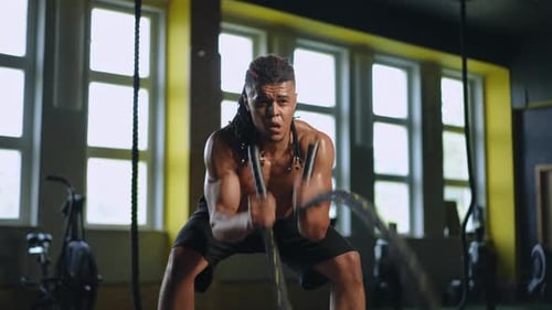Muscular Man Exercising With Battle Ropes at Gym