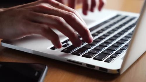 Young Man Works Typing on a Laptop Keyboard Closeup