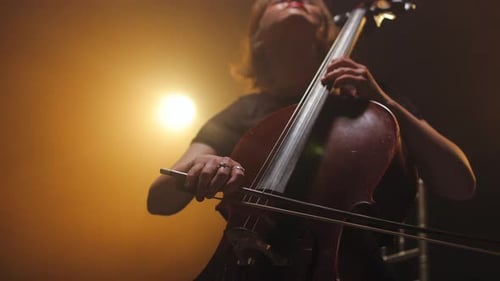 Woman Plays Cello on Stage in Dramatic Lighting