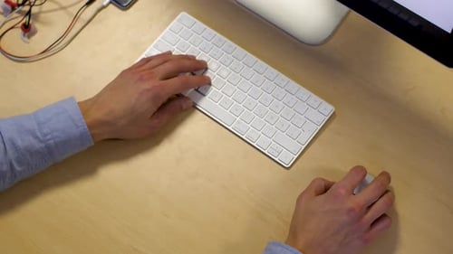 Men's hands typing on a white keyboard