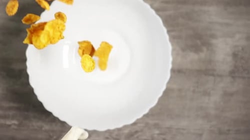 Cornflakes and Milk Pouring into White Bowl
