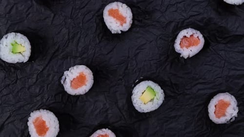 Sushi Maki Rolls on Rotating Black Background Top View Fashion Food Background