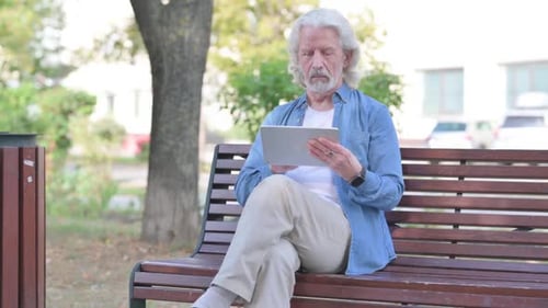 Senior Man Using Tablet on Park Bench