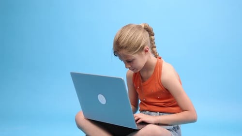 Girl Using Laptop Computer Sitting Cross-Legged Indoors